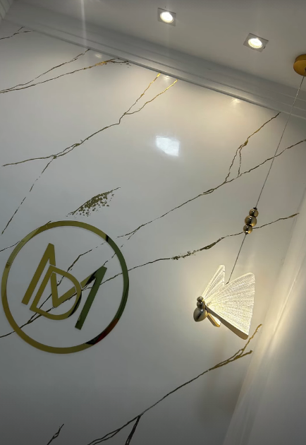 Parede marmorizada, marca dourada e iluminação do estúdio Marinho Design