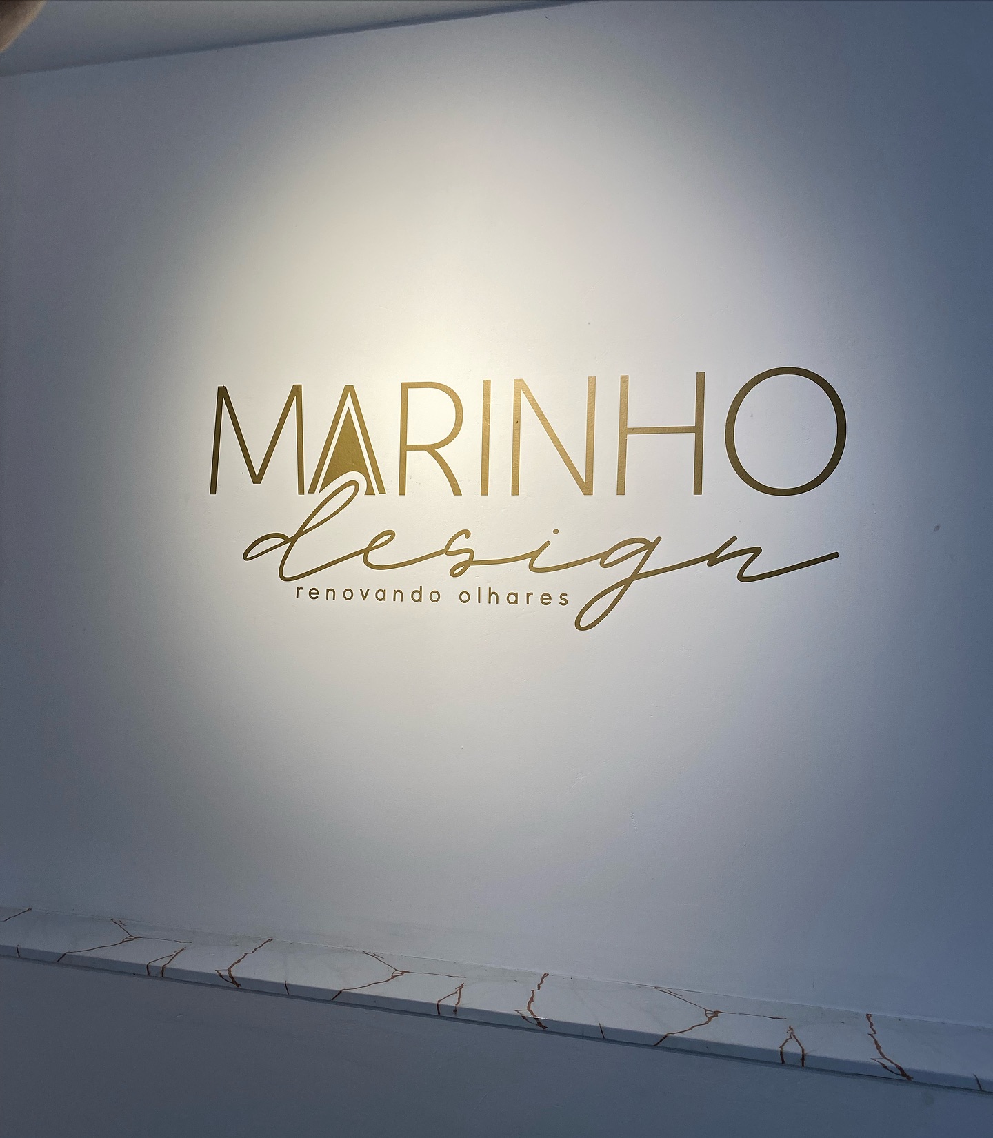 Identidade dourada da Marinho Design na parede do estúdio